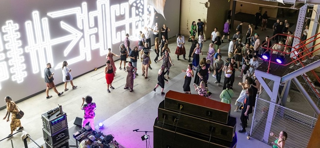 Audience gathered near the stage during a live DJ performance at the Biennale opening event