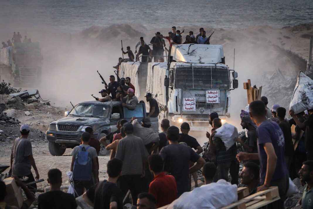Armed Palestinians sit on trucks carrying humanitarian aid