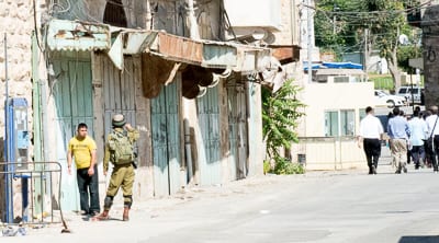 A member of the IDF counsels a Palestinian youth with Downes Syndrome who has wanf=dered into the Jewish sectin of Hebron Photo: Henry Benjamin